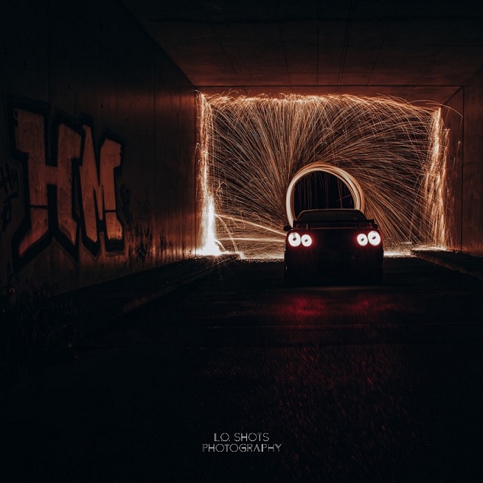 fahrzeugfotografie_nissan_steht_in_einem_dunklen_durchgang_mit_funkenring_im_hintergrund